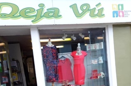 Charity shop storefront with open door and clothes in the window