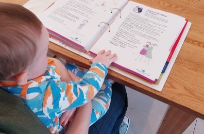 Toddler in Parents lap reading family support material