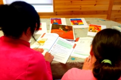 Adult teaching child from text book at a desk